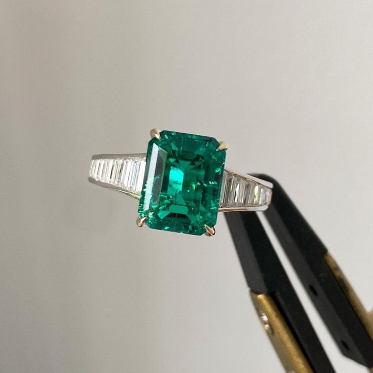 an emerald and diamond ring is being held up