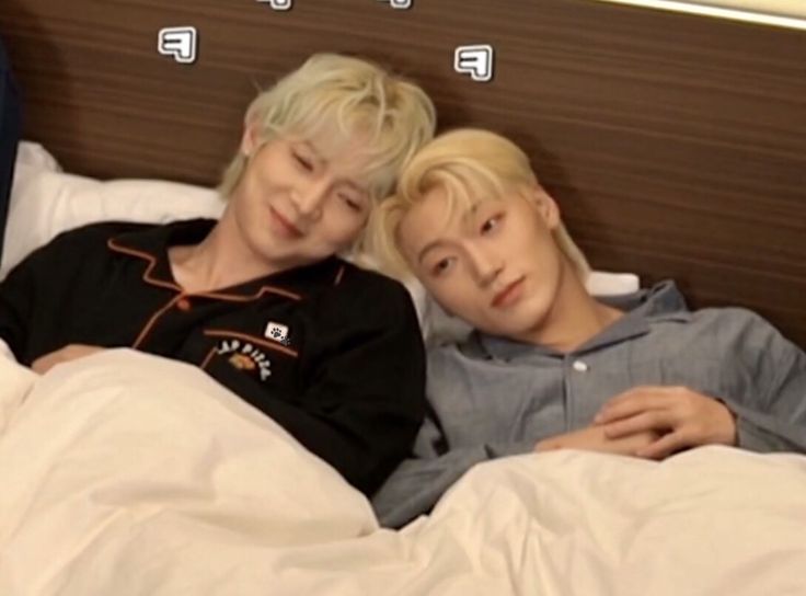 two young men laying in bed next to each other with their arms around each other