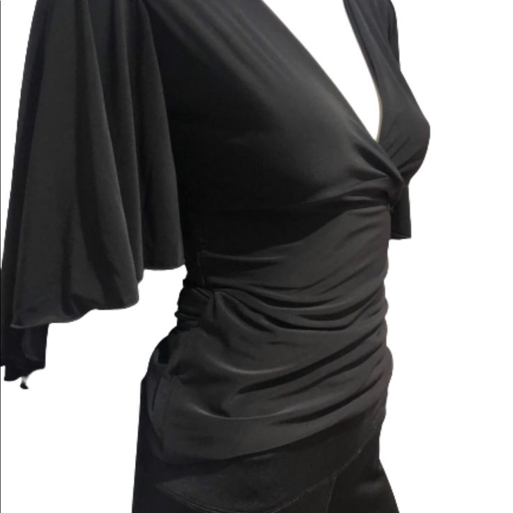 This New With Tags Wrap Blouse Has A Hook Closure To Keep Busy In Place And Long Drape Tie, Gorgeous Flutter Sleeves For Eye Catching Spins And Shines On The Dance Floor. Soft Black Material Complements Any Skirt Or Pants. Excellent Day To Night Staple. Black Ruched Tops For Evening, Black Fitted Draped Top, Elegant Black Ruched Tops, Stretch Ruched Blouse For Party, Black Ruched Tops For Party, Black Stretch Draped Top, Black Draped Stretch Top, Elegant Ruched Blouse For Evening, Elegant Formal Blouse With Ruched Details