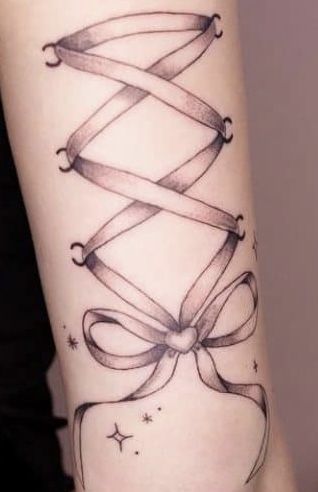 a woman with a tattoo on her arm that has a ribbon wrapped around the wrist