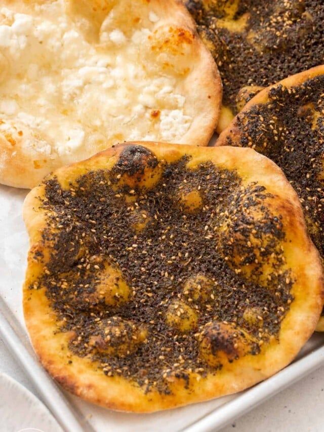 baked bread with cheese and black pepper sprinkled on it in a white tray