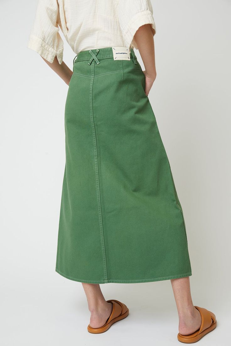 High waisted skirt - Relaxed fit- Fitted waist, Mid length skirt- Garment dyes with a front buttons made of recycled paper- Belt pulls on the waist- Two side pockets, one leg pocket, two back pockets Fabric Note Cotton 100%Machine wash gentle / Tumble dry low / No bleachWarm iron if neededDry clean optionalMade in U.S. Tanna Midi Skirt, Mid Green Skirt, Green Mid Skirt, High Wasted Skirt, Wardrobe Building, Mid Length Skirt, Twill Skirt, Cotton Midi Skirt, Skirts Midi High Waisted