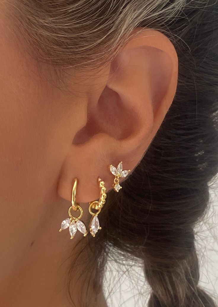 a close up of a woman's ear wearing gold earrings with crystal flowers on them