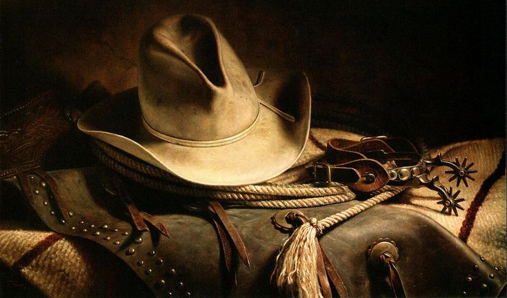 a cowboy hat sitting on top of a brown leather bag with tassels around it