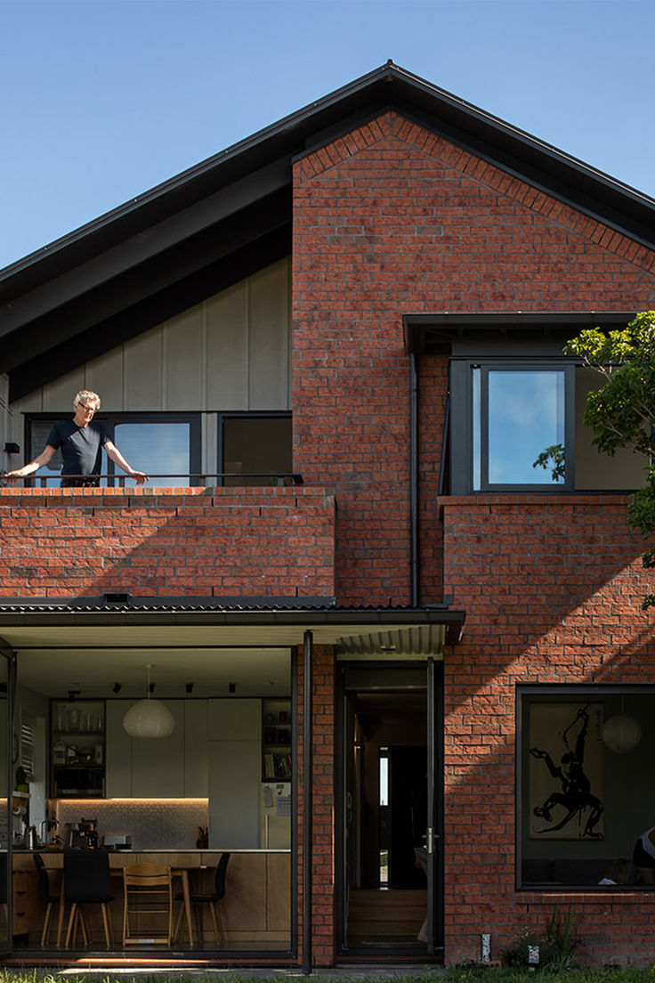 a woman standing on the balcony of a brick house