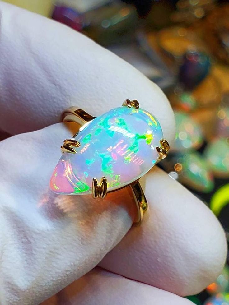 a person holding an opal ring in their hand