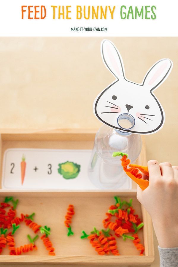 a child's hand holding carrots in front of a bunny game