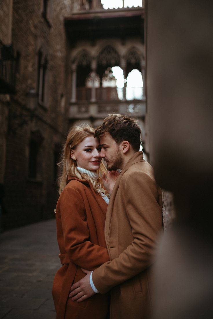 a man and woman standing next to each other in front of an old brick building