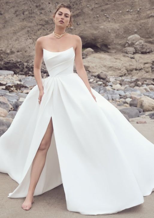 a woman in a white dress standing on the beach