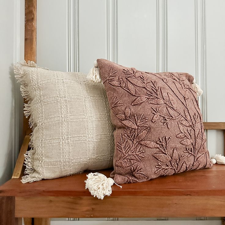 two pillows sitting on top of a wooden bench