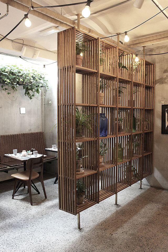 a room divider made out of wooden slats with plants on top and hanging from the ceiling