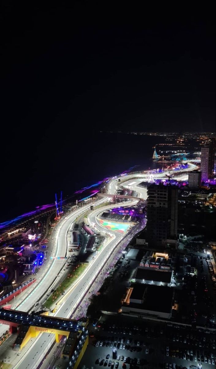 an aerial view of a city at night with cars on the road and buildings lit up