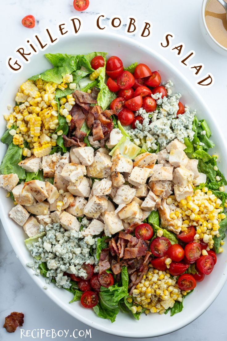 a salad with chicken, tomatoes, corn and lettuce in it on a white plate