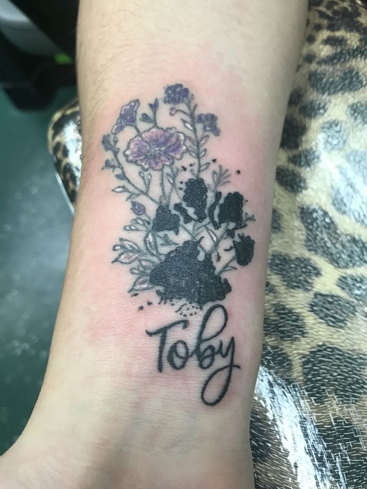 a flower tattoo on the wrist that says, toby with flowers in black ink