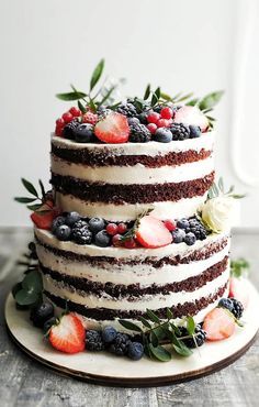 a triple layer cake with berries and strawberries on top