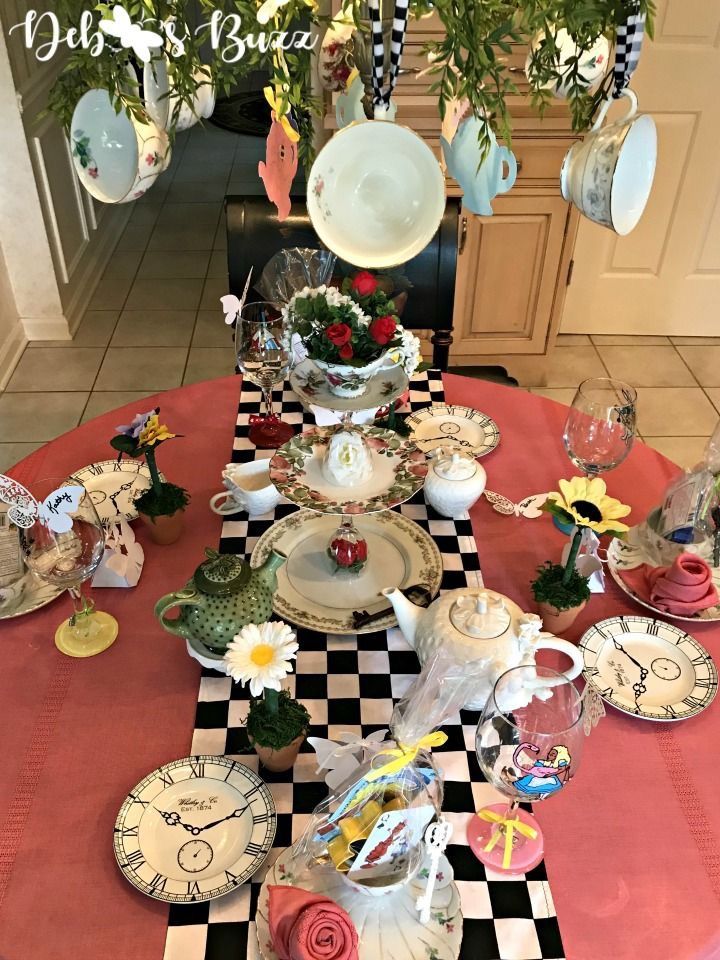 a table topped with plates and cups covered in flowers on top of a checkered table cloth