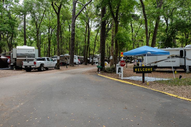 an rv park with several vehicles parked in the parking lot and trees lining the road