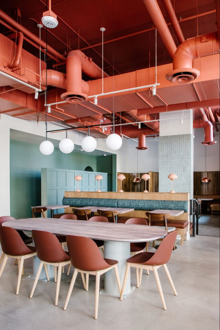 a large wooden table surrounded by chairs and lights in a room with exposed ceiling beams