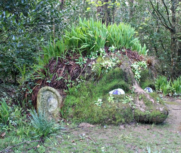 an animal made out of moss in the middle of some trees and grass with plants growing on it