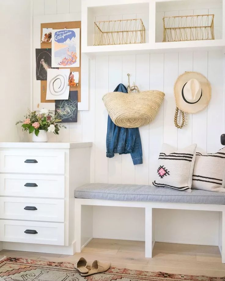 a white bench sitting next to a wall filled with hats and other items on top of it