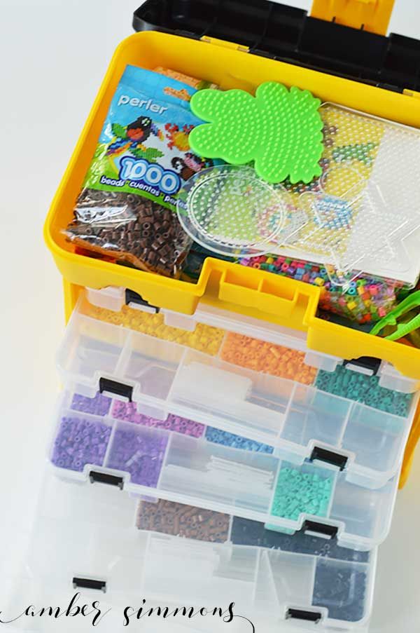 a yellow plastic box filled with lots of crafting supplies on top of a white table