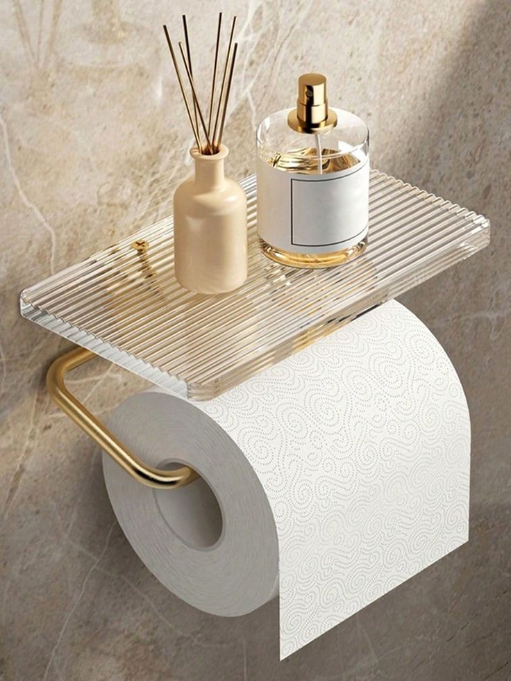 a toilet paper holder with two rolls of toilet paper on it and a bottle of perfume next to it