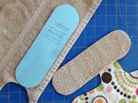 an oven mitt and pot holder on a cutting board with a blue cloth backing