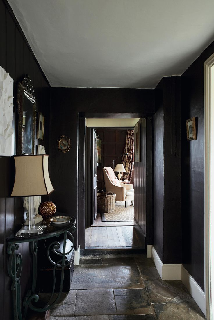 a hallway with dark wood paneling and white trim on the walls, along with two lamps