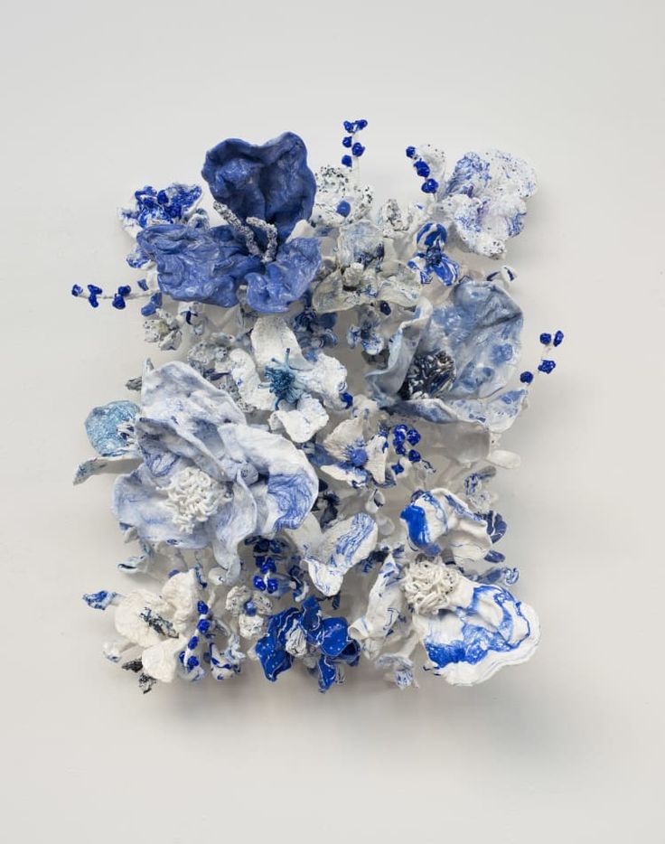 an arrangement of blue and white flowers on a white surface