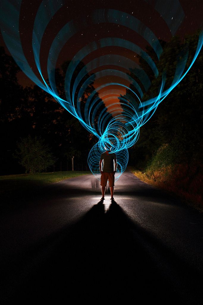 a person standing in the middle of a dark road with blue lights on their face