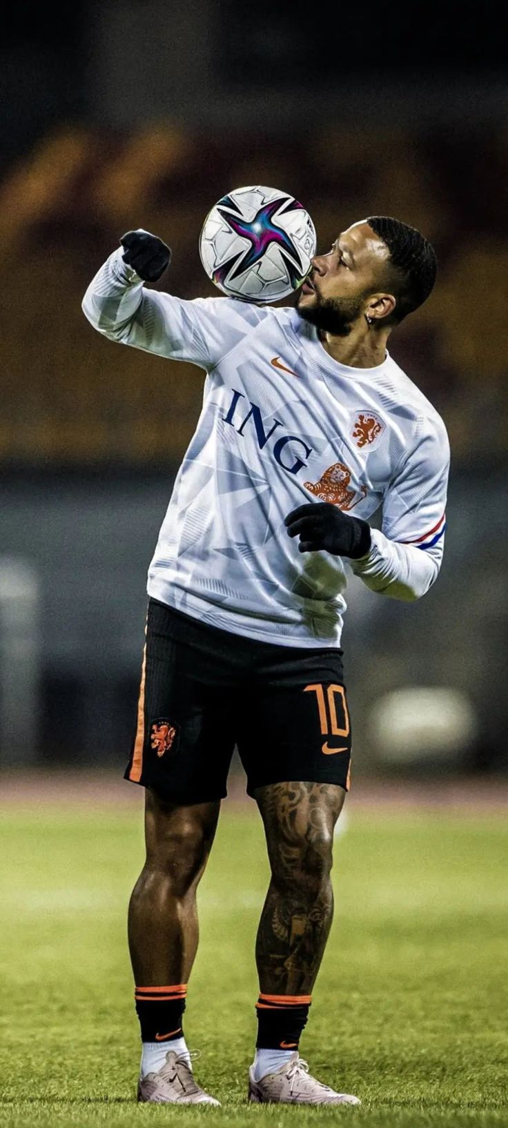 a man with tattoos on his arms and legs, holding a soccer ball in the air