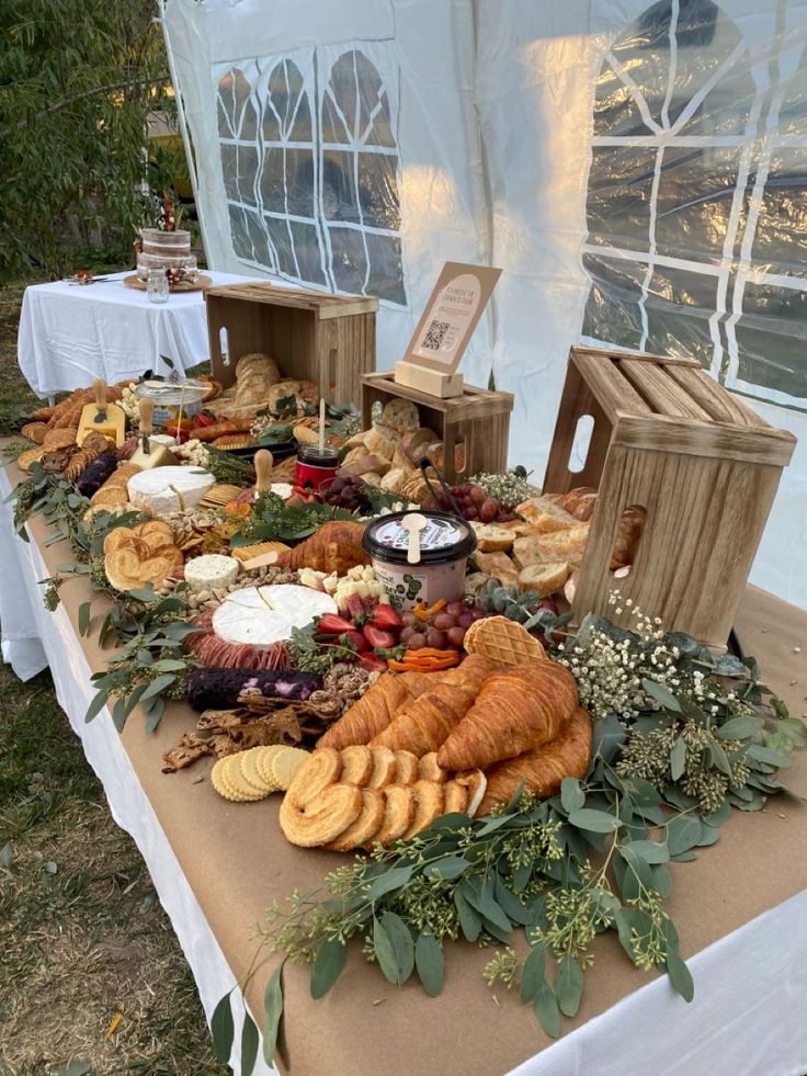 a table topped with lots of food next to a white awning covered in windows