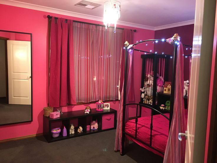 a bedroom with pink walls and lights on the ceiling, bed in front of a mirror