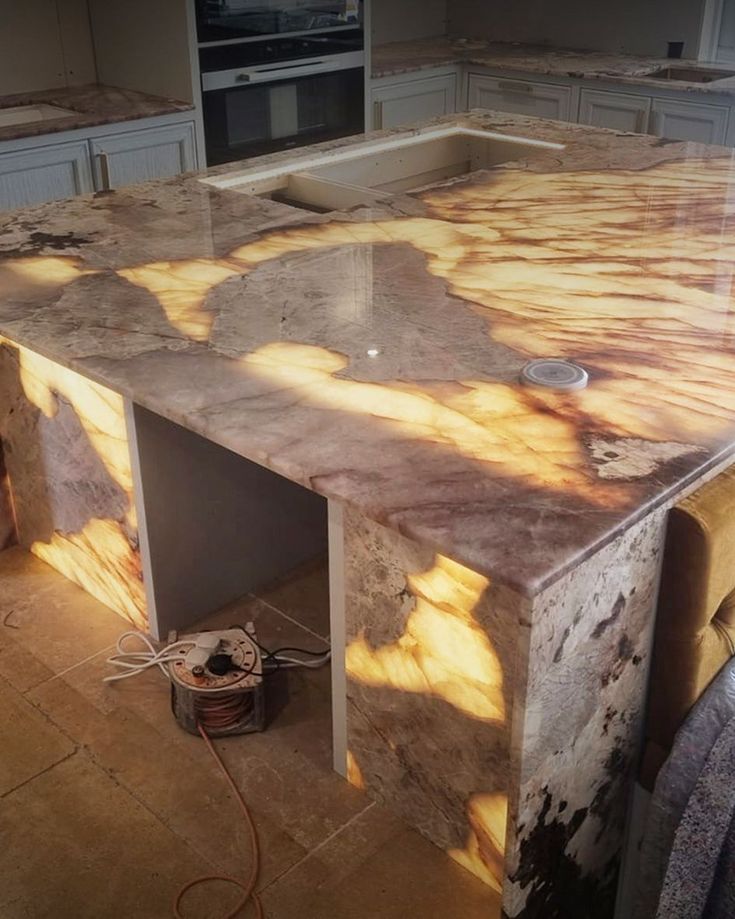 a marble counter top in a kitchen with sunlight coming through the window and onto the floor