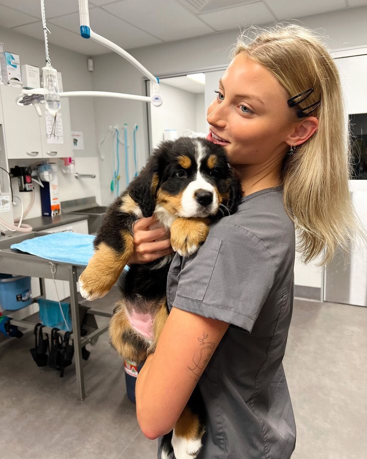 a woman holding two puppies in her arms at the veterinator's office