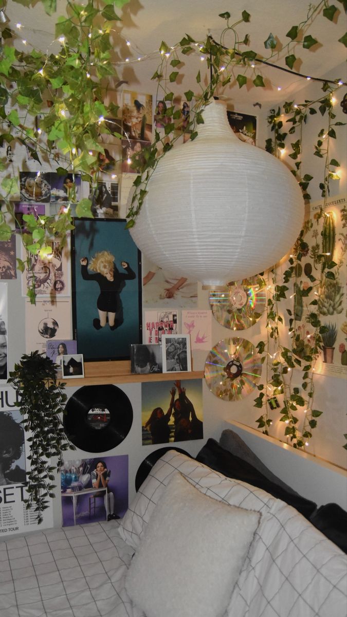 a bedroom with plants hanging from the ceiling and various pictures on the wall above it