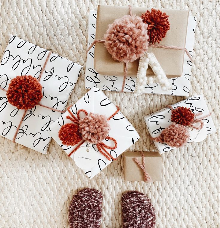 presents wrapped in brown and white paper with pom - poms