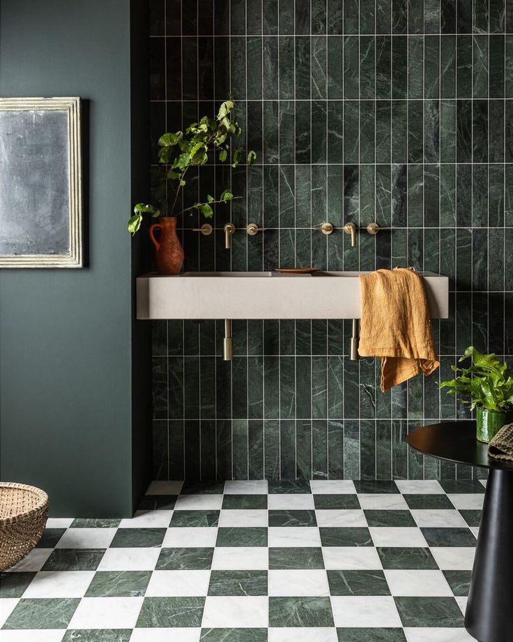 a black and white checkered floor in a bathroom with green tiles on the walls