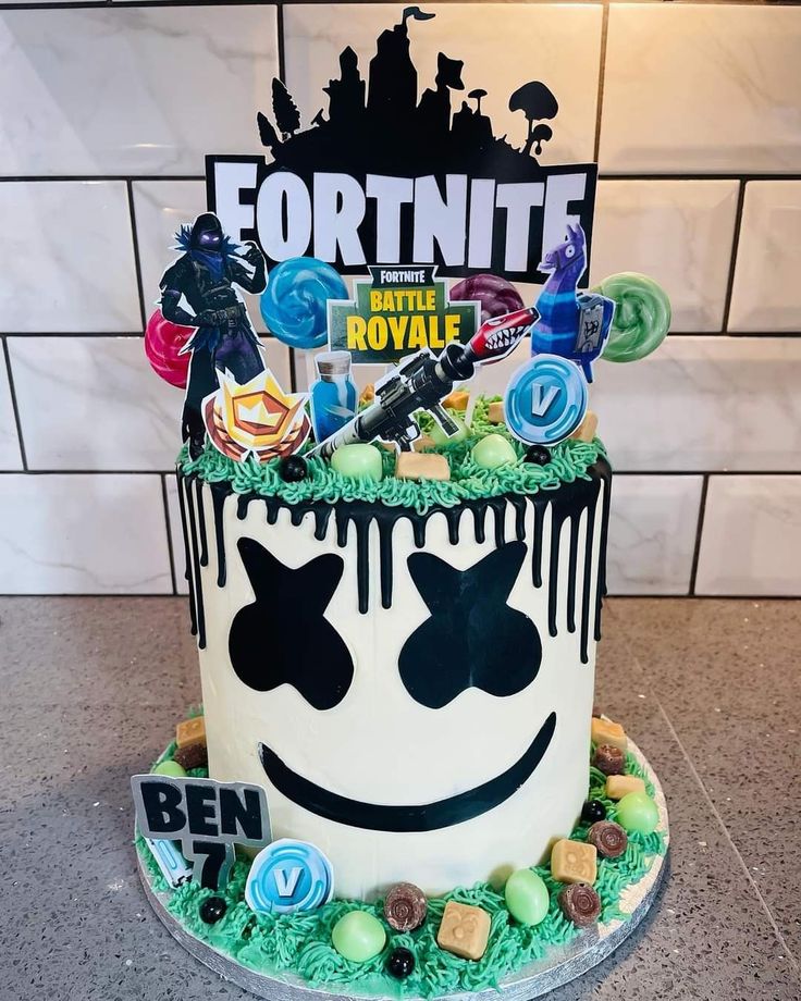 a birthday cake decorated with an image of fortnite and lollipops