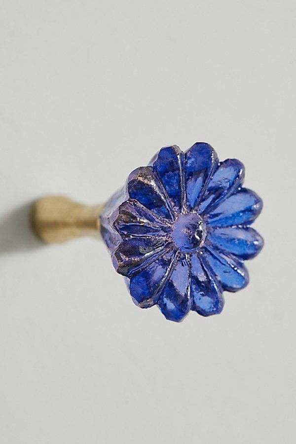 a blue flower ring sitting on top of a white table next to a wooden stick