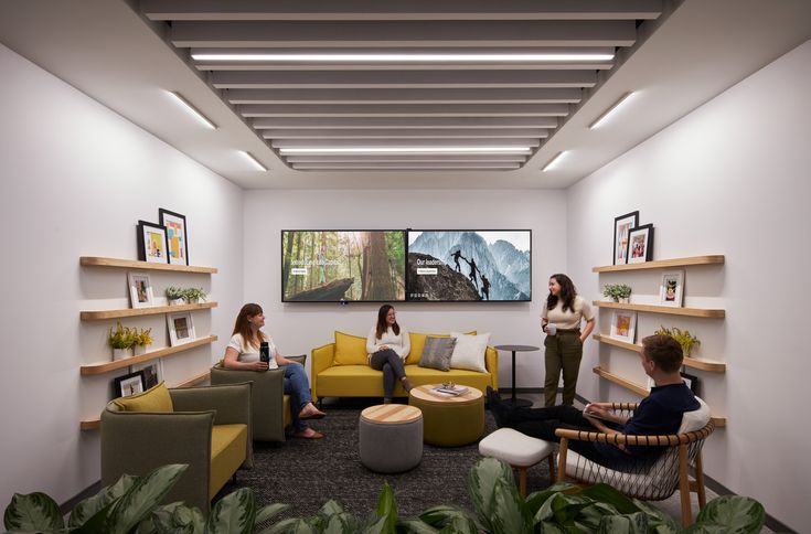 three people are sitting in a room with yellow furniture and pictures on the wall behind them