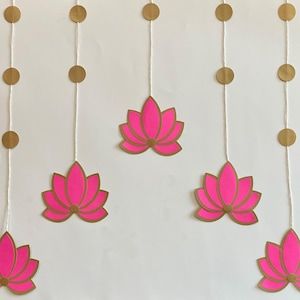 pink and gold paper flowers hanging from strings on a white wall with circles around them