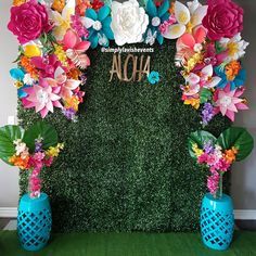 the backdrop is decorated with artificial flowers and greenery for an aloha party