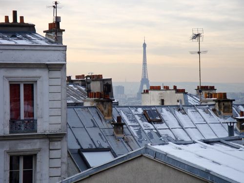 rooftops with roofs covered in snow and the eiffel tower in the distance