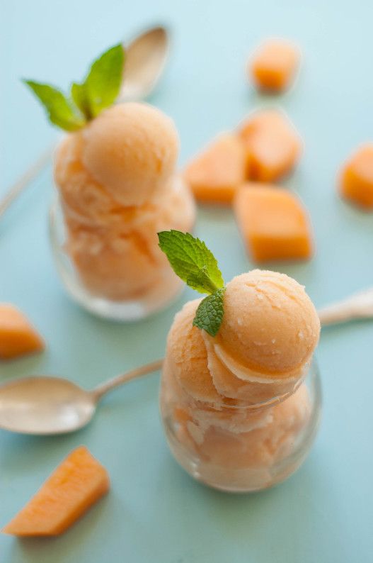 two scoops of ice cream with mint on top and carrot chunks in the background