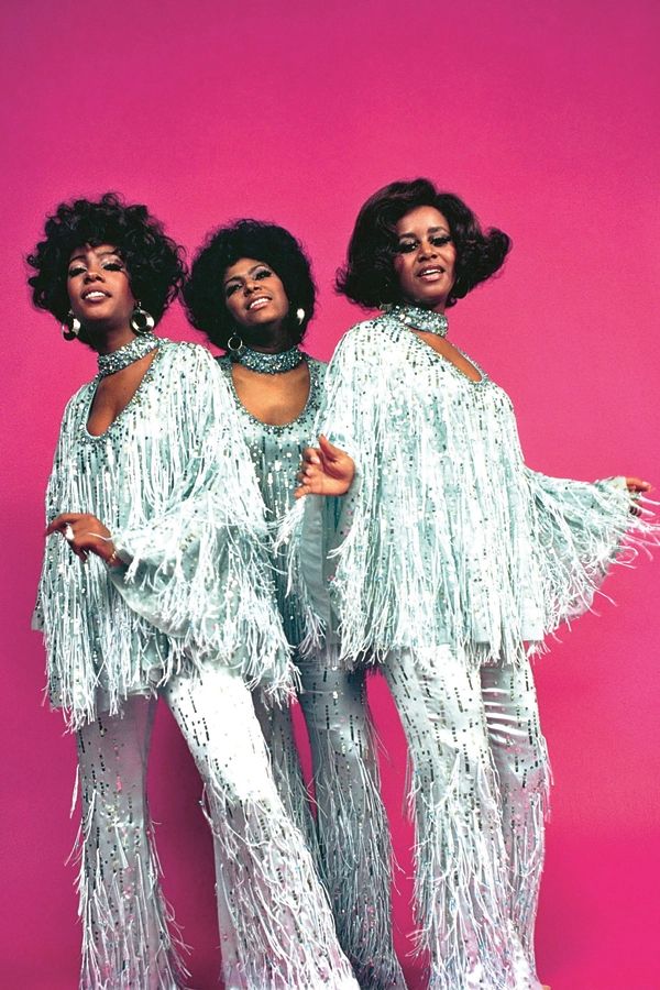 three women in white fringed outfits posing for the camera