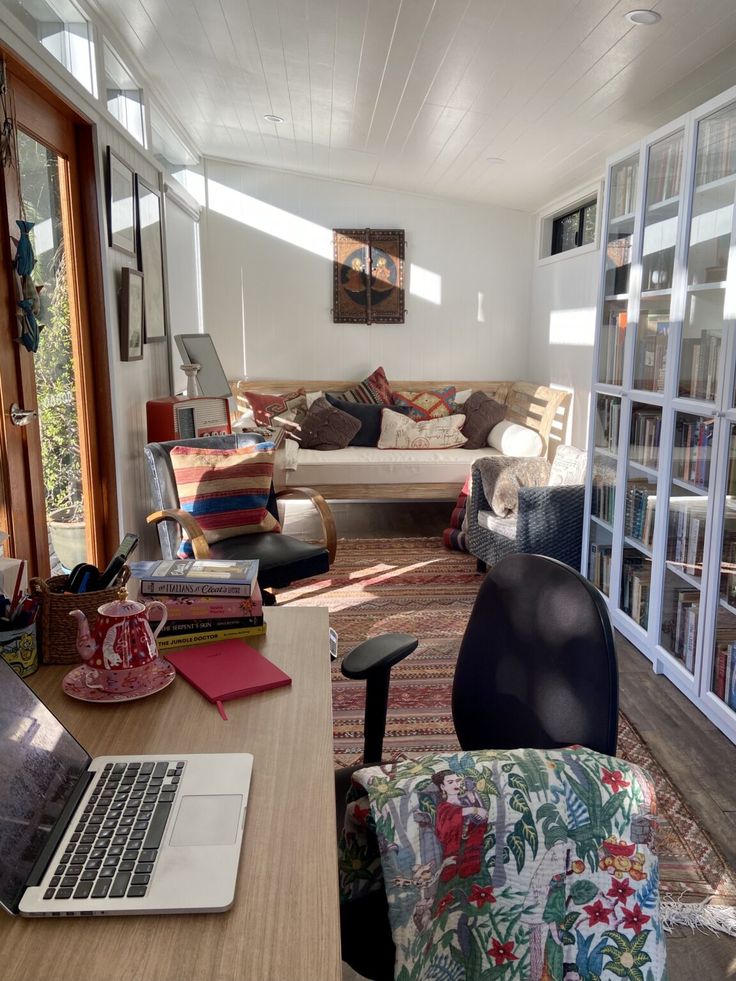 a living room filled with furniture and a laptop computer on top of a wooden table