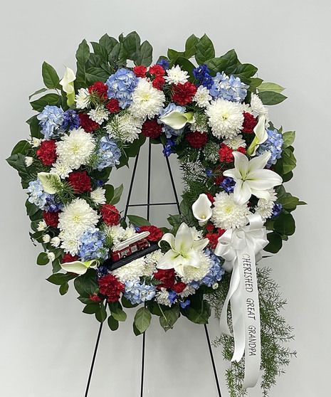 a wreath with red, white and blue flowers is on display in front of a wall