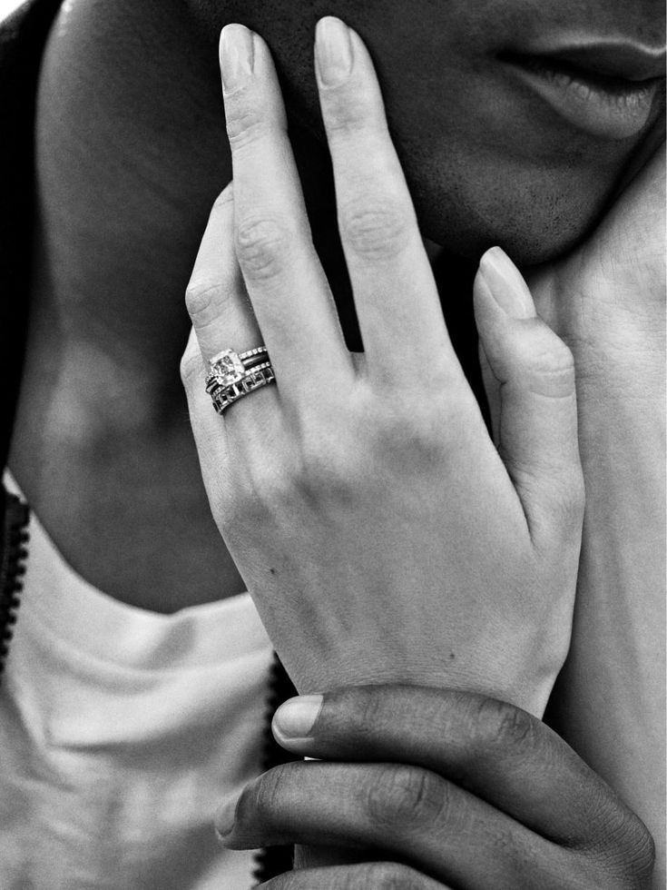 a woman holding her hand up to her face with a ring on it's finger