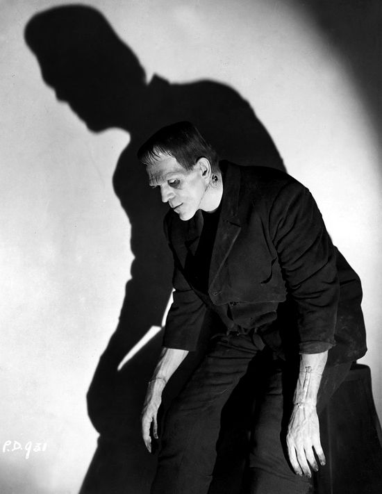 a black and white photo of a man with his shadow on the wall